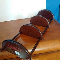 Full view of the wooden display shelf showing three semi-circular holder sections and original Bombay Company label on bottom.