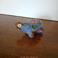 Close-up image of the blue cloisonne turtle figurine displaying detailed floral and butterfly patterns with gold accents.