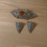 Front view of rhinestone brooch and pair of matching fur clips on wood surface