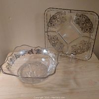 Two glass serving dishes with silver floral overlay, one bowl and one divided square platter