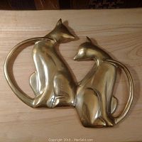 Front view of solid brass cat wall art sculpture showing two cats with curved tails forming an oval shape.