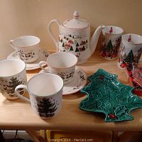 Full set of Christmas dishes including teapot, cups, mugs, and candy dish shown on table.