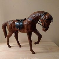 Full side view of the leather horse sculpture showing posture and details of the harness and saddle.