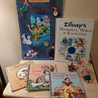 Five vintage Disney children's books including Peter Pan, 101 Dalmatians, Pinocchio, Scamp, and Snow White arranged on a flat surface with visible signs of wear on covers and pages.