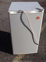 White Igloo bar fridge front view with power cord draped over door handle, showing clean condition and logo.