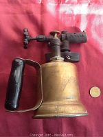 Full photo of the vintage gas torch showing brass body, handle and gas valve, approximately 8 inches tall with a coin for scale