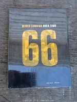 Front cover of the book showing title and 66 in gold lettering on black background, sealed in plastic wrap.