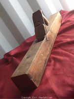 Side view showing wooden body, handle, and iron blade of the antique hand planer, highlighting some wear.