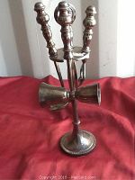 Front angle of the bar set showing the stand, bar tools, and jiggers on red fabric.