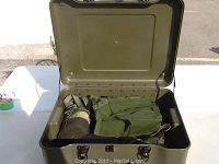 Open green hard case displaying inside contents including a green fabric pouch and a gas mask.