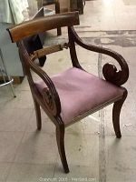 Full view of Victorian rosewood chair showing curved armrests with scroll design and upholstered seat.