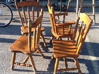 Four oak chairs arranged outdoors, showcasing the group with three side chairs and one armchair.