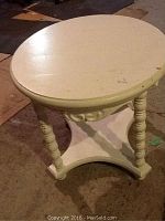 Full view of the small round white painted end table showing the table top and legs