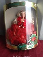 Barbie doll in original box showing front view of doll in red holiday gown with gold accents.