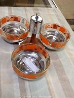 Overview of the Lazy Susan with three glass dishes on a table showing the central stainless steel base and handle along with the dishes.