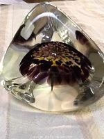 Top angled view of the signed glass paperweight showing the detailed flower inside surrounded by clear glass.