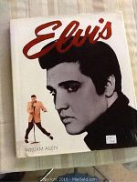 Front cover of the book featuring a large black and white profile image of Elvis Presley with his name in red script and a smaller color image of him performing.