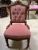 Front view of the antique East Lake upholstered chair showing pink velvet tufted backrest, carved wood frame and seat upholstery.