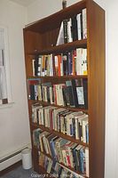 Full view of the tall wooden bookcase filled with books to demonstrate shelf size and spacing.