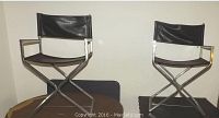 Pair of vintage director chairs side by side showing black leather seats and backs on chrome metal frames.