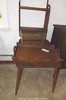 Photo showing oblong teak table with turned legs and brass tips, adjacent to wooden tray and vintage roll top wooden rolodex, with wall mount shelf behind