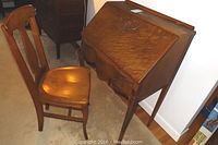 Angle view of drop-front desk open with matching chair placed beside