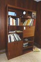 Full view of wooden bookcase with books on shelves and three doors below.