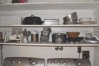 Shelves containing various kitchen items including baking pans, kitchen appliances, and cookware