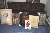 Photo showing all five framed prints displayed standing on carpet against a wall, varying sizes and frame styles visible.