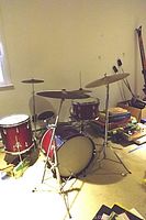 Full view of the Remo Weather King drum set showing bass drum, floor tom, mounted tom, snare drum, two cymbals on stands, and surrounding environment