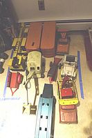 Overview of all ten tin trucks and cars arranged on floor, showing their sizes and conditions