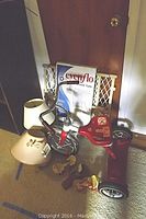 Photo of AMF red tricycle, Evenflo baby gate in box, two lamps with beige and cream shades, and other items on floor next to door