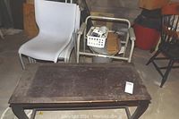 Toilet seat, Omron blood pressure monitor in basket, and part of piano bench and chairs shown around table.