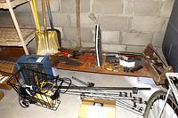 Photo showing assorted hand tools including hammers, clamps, and other tools arranged on a shelf and in baskets near garden tools.