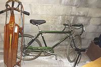 Photo showing the green Schwinn Sport Collegiate bicycle standing beside the wooden Flexible Flyer sled leaning against a concrete wall.