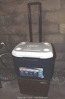 Coleman 5.5 quart Xtreme cooler in navy blue with white lid, telescoping handle and wheels.