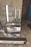 Two unopened Craftsman garage door opener boxes with model 953310 and two long boxed rails, accompanied by a Titan electric heater placed on the floor against a concrete block wall.