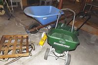 Photo showing all three items together: edge spreader, wheelbarrow, and wooden dolly