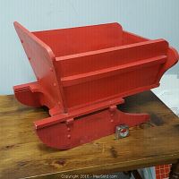 Side angle view of the red wooden sleigh showing the runners and side panels.