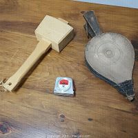 Photo of wooden mallet and fire bellow with a small tape measure for scale on wooden surface.