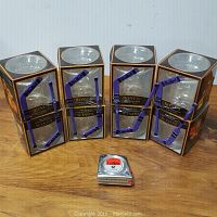 Four boxes each containing a clear Crown Royal etched glass and a purple hockey stick stir stick, boxed and new.