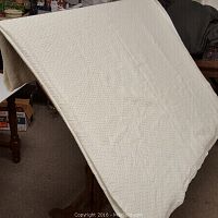The entire blanket displayed hanging to show size and texture with subtle chevron weave in cream color.