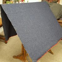 Blue wool blanket draped over a chair, showing the texture and red edging.