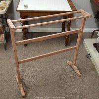 Front and side view of the wooden blanket or quilt stand showing overall structure and condition.