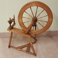 Front-right perspective showing full spinning wheel with drive wheel, maiden, bench and base
