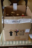 Closed cardboard box with tape and labels, box contains candlesticks.