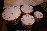 Image showing stacks of dinner plates, luncheon plates, side plates, and fruit nappies with floral pattern and gold edges.