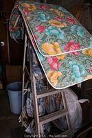 Photo showing aluminum step ladder with floral cushions draped over it.