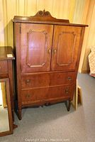 Full front view of wooden wardrobe with carved top, twin doors, and lower drawers