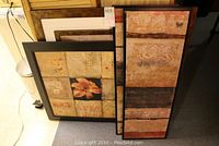 Four decorative wall art pieces leaning against furniture showing all items in lot